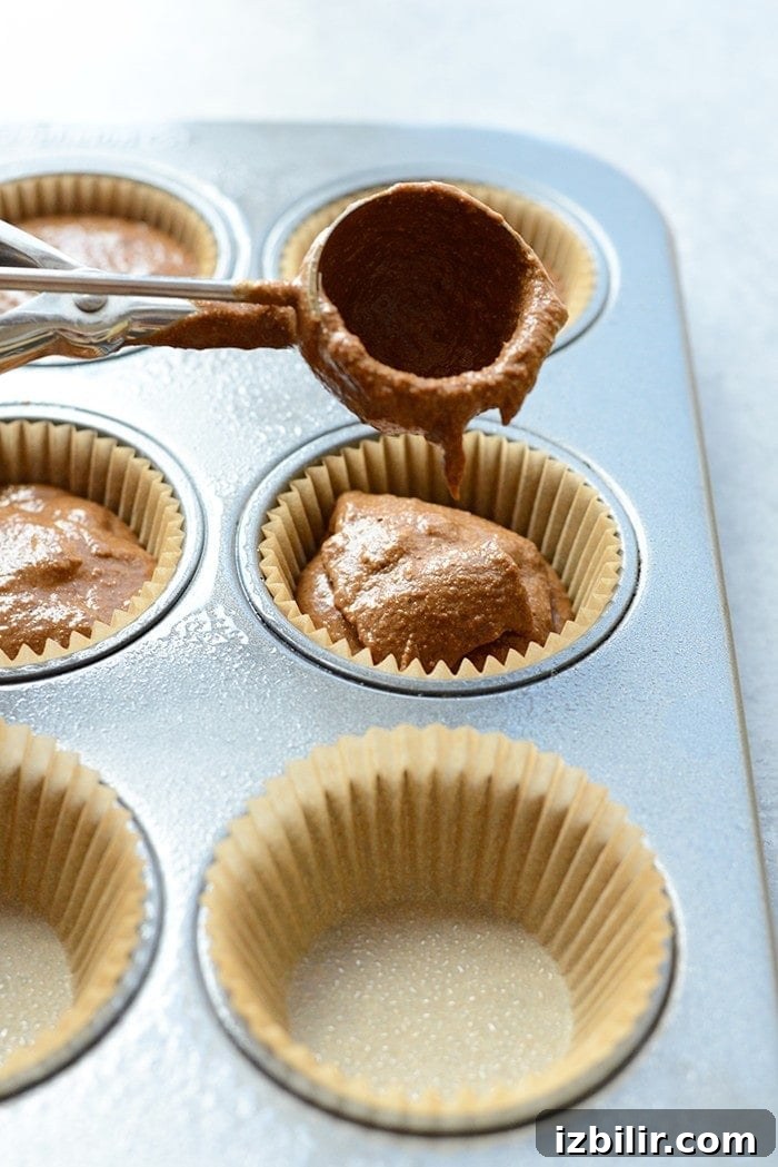Scooping pumpkin chocolate batter Chocolate pumpkin batter being scooped into a muffin tin