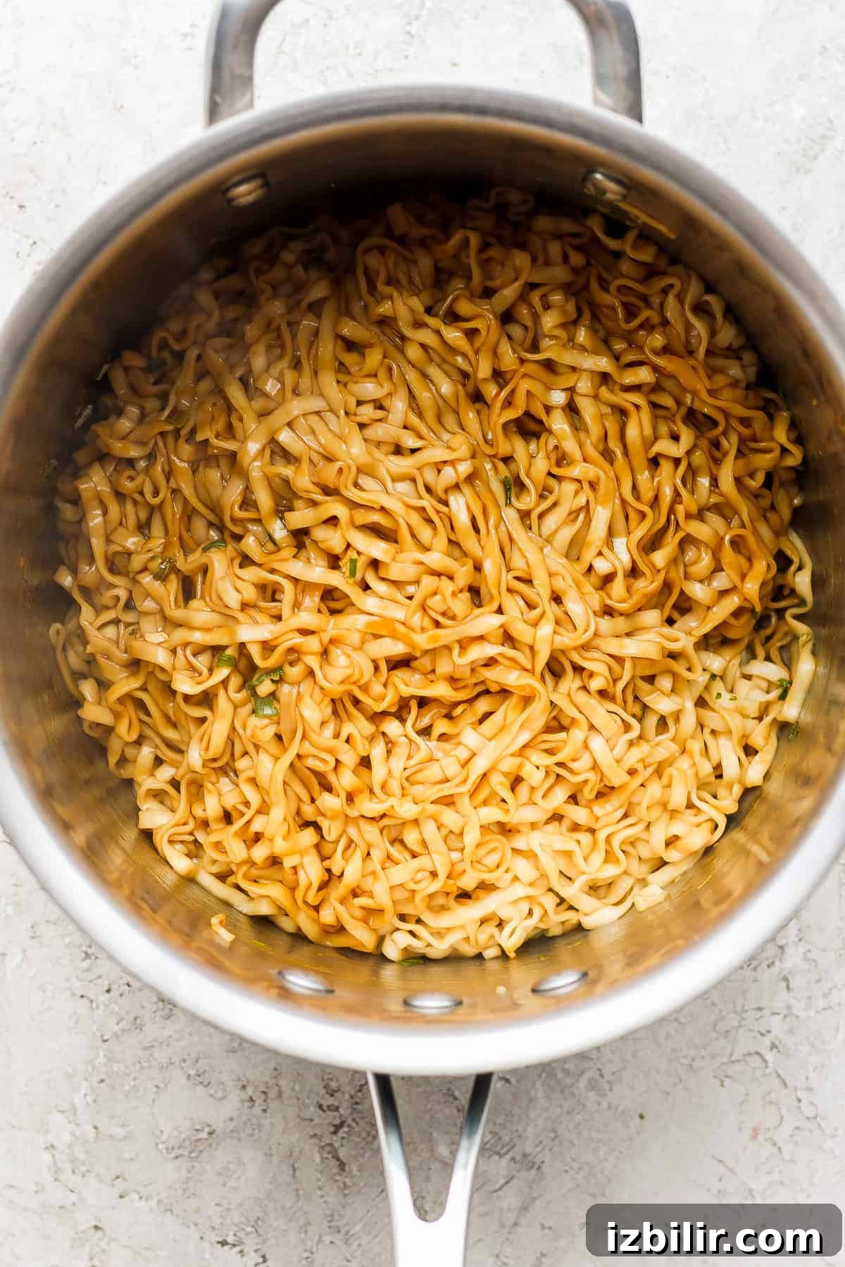 a pan with noodles in it on a white surface.