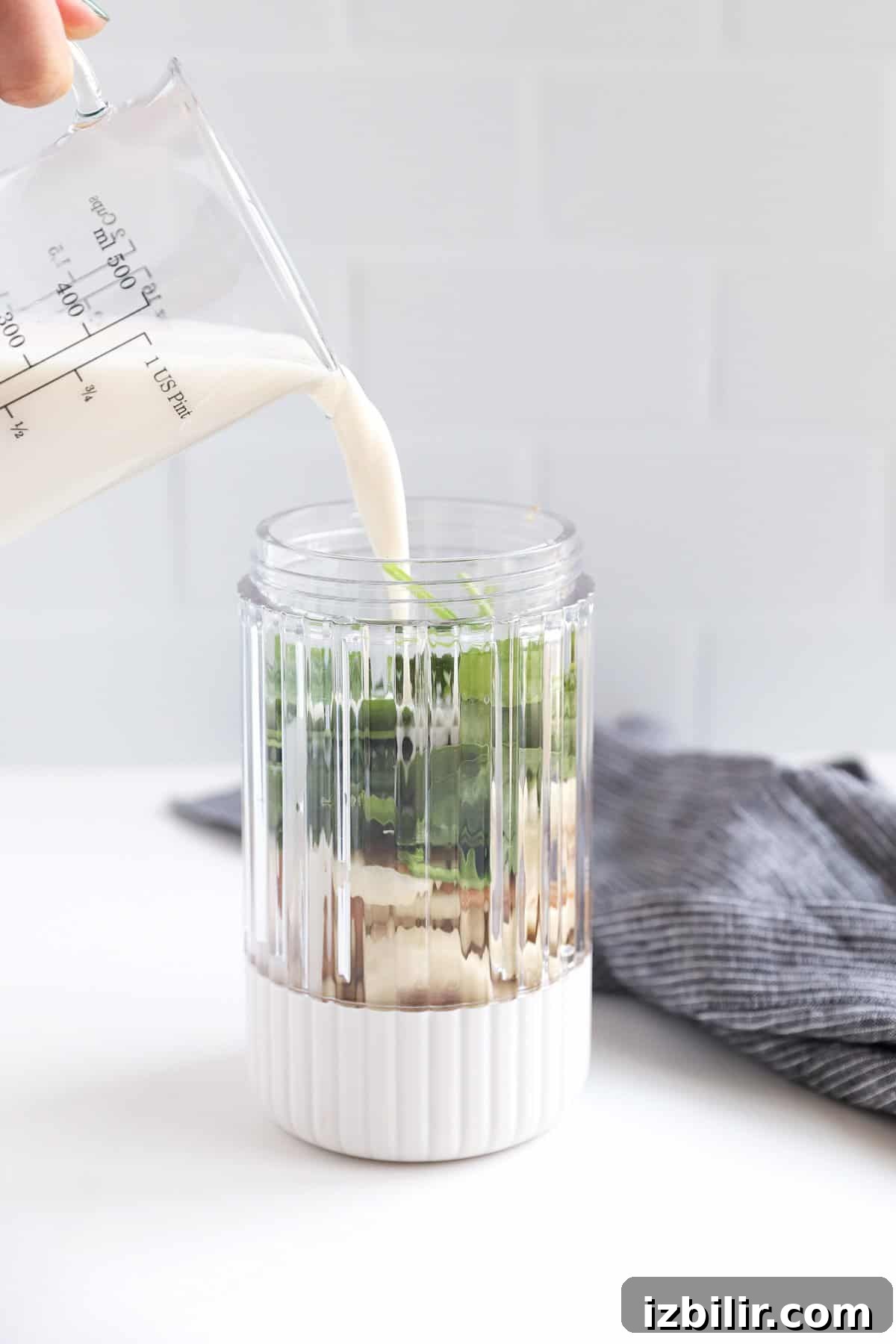 A person pouring milk into a glass jar.