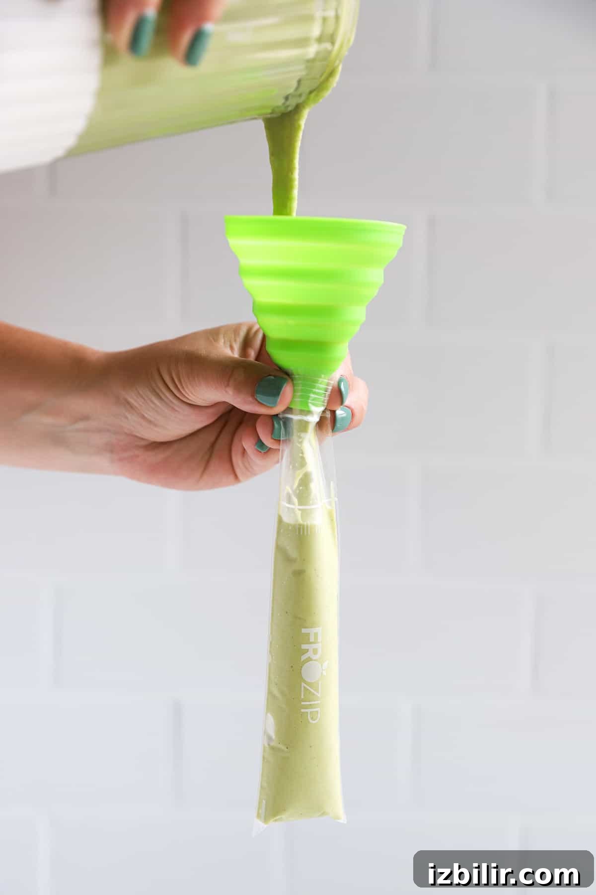 A person pouring a green liquid into a plastic container.