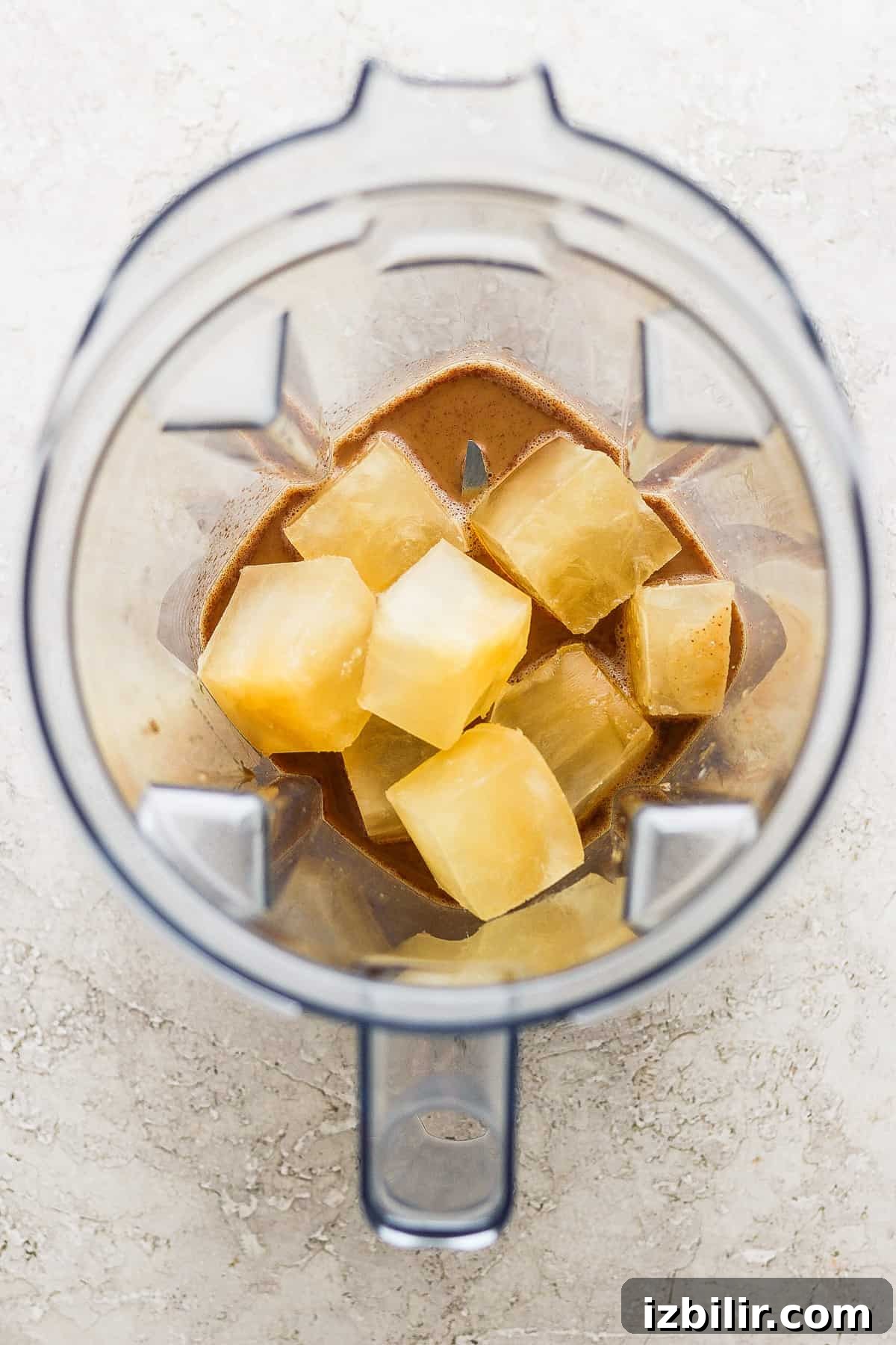 A blender with chunks of pineapple in it.