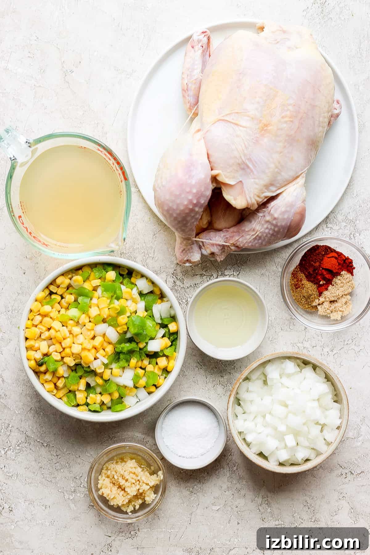 a chicken, corn, onions and other ingredients on a table.