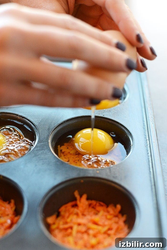 Sweet Potato Hash Egg Muffins Recipe 3 Cracking an egg on top of sweet potato hash in a muffin tin