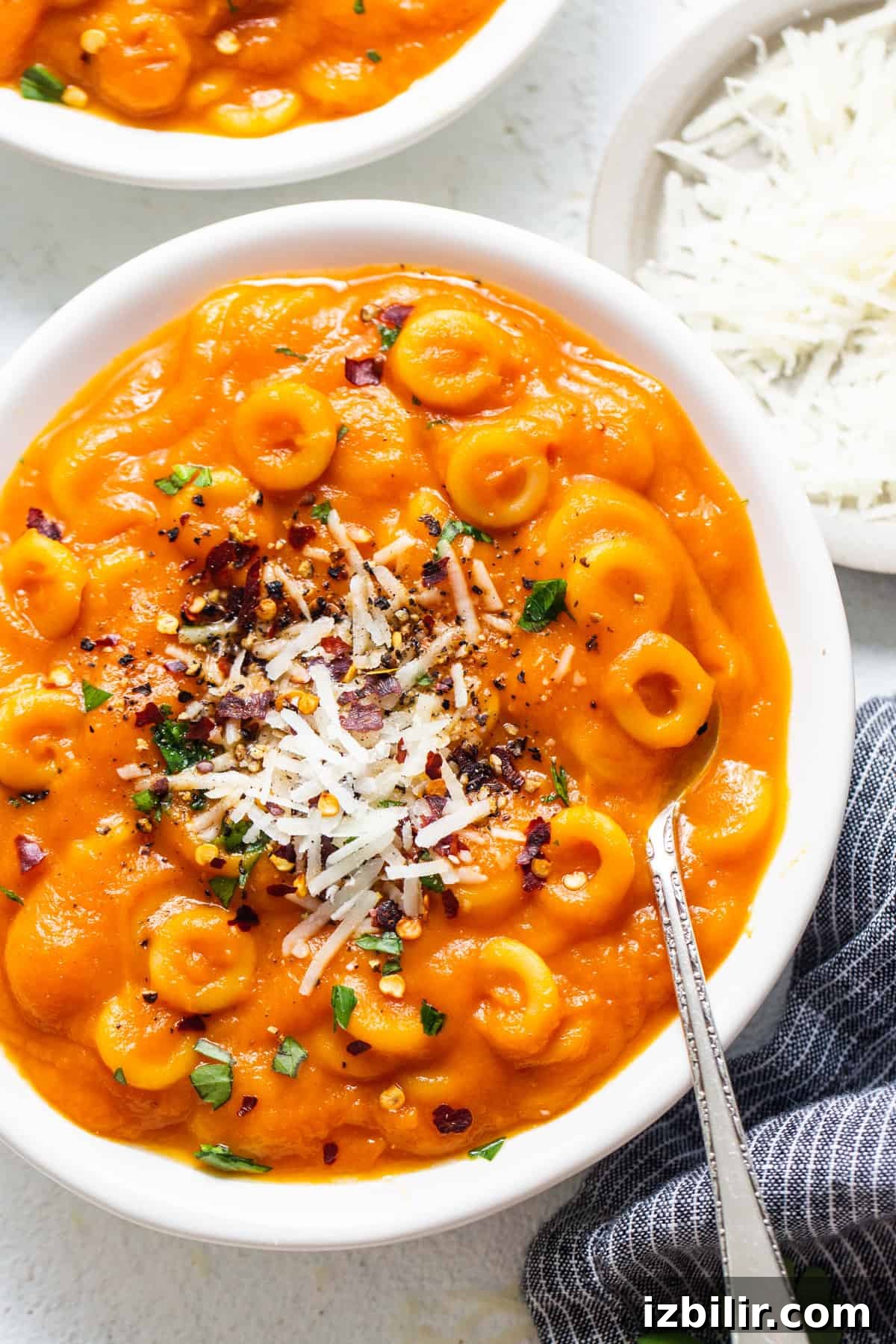 Two bowls filled with pasta and cheese on top of a table.