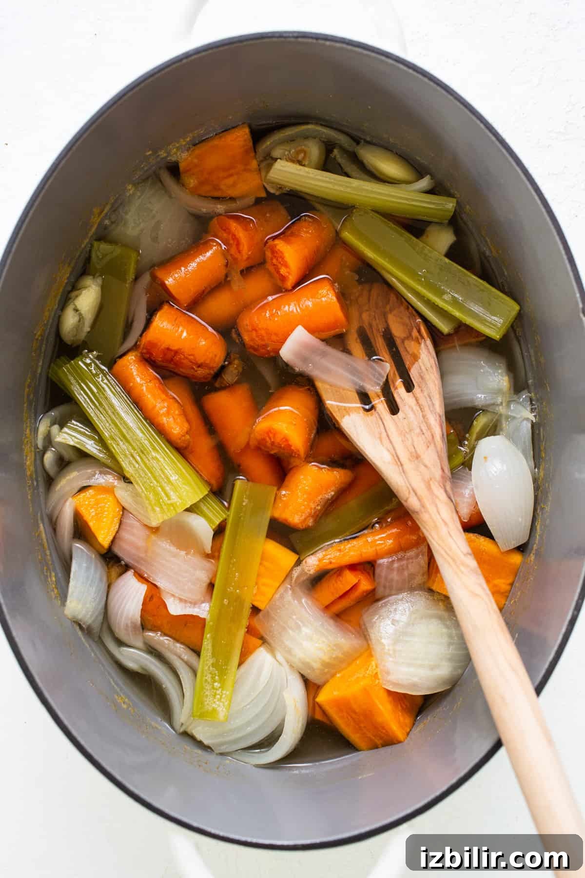 A pot filled with carrots, celery and onions.
