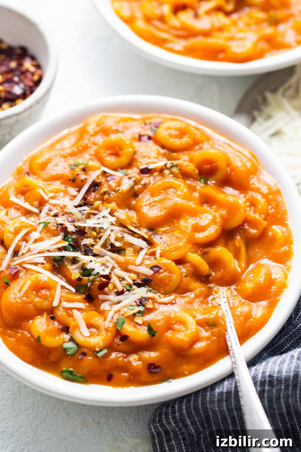 A bowl of macaroni and cheese soup with a spoon.