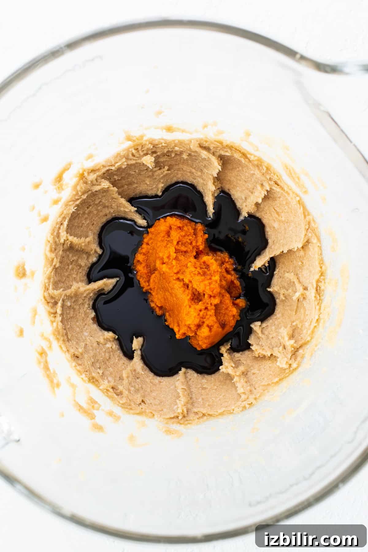 A glass bowl filled with a mixture of peanut butter and orange juice.