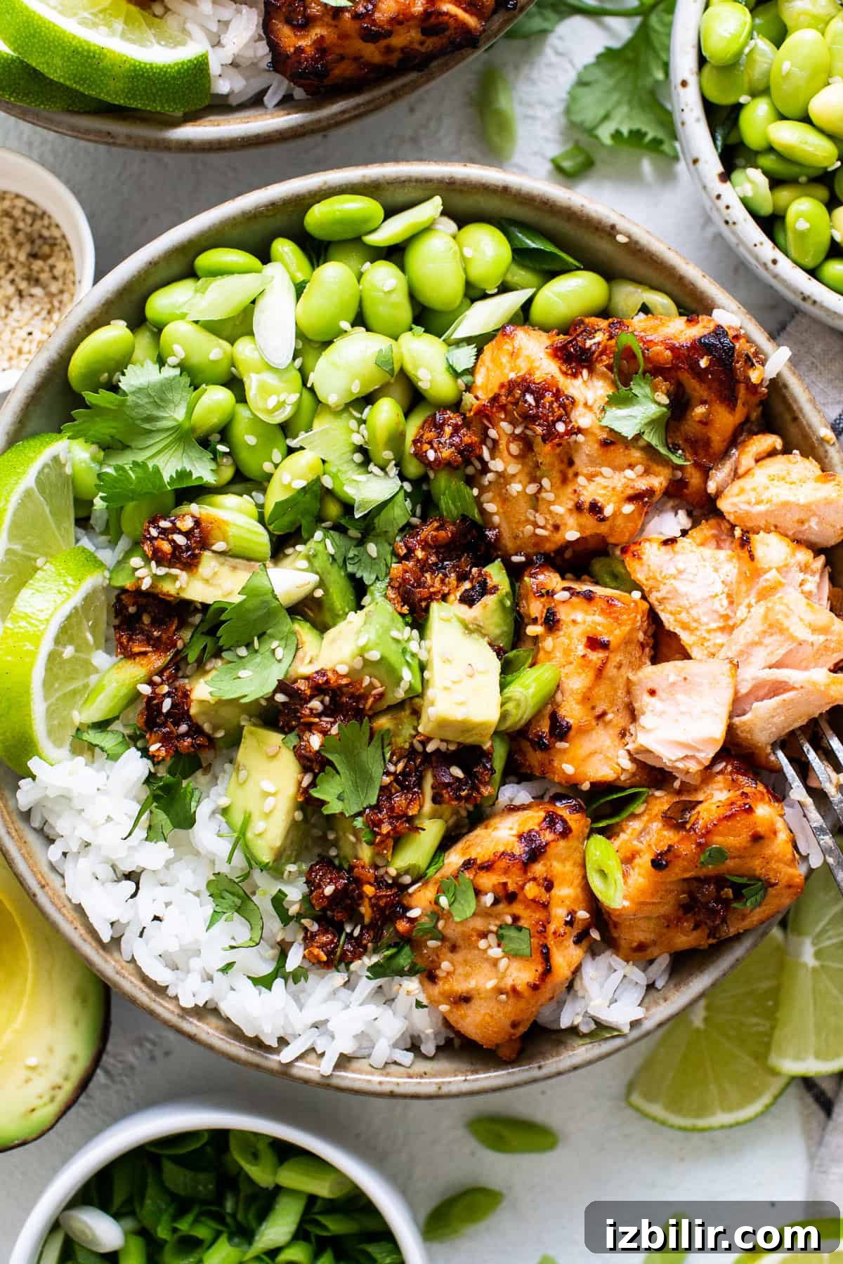 Crispy Air Fryer Honey-Chili Crunch Salmon Bites 2 Bowl with salmon bites, rice, edamame salad and lime.