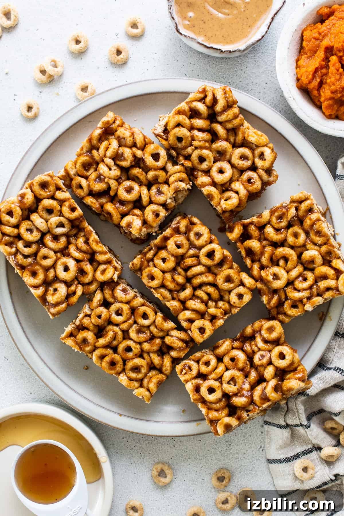 A plate with a plate of cereal bars and a bowl of peanut butter.