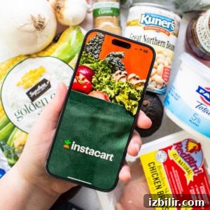 A person holding up a phone with groceries on it.