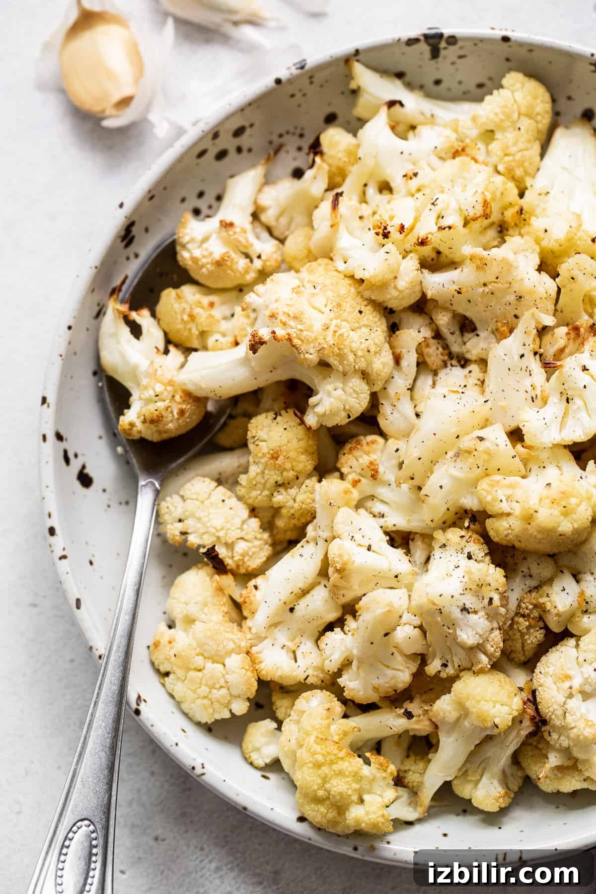 Roasted cauliflower in a bowl with a spoon.