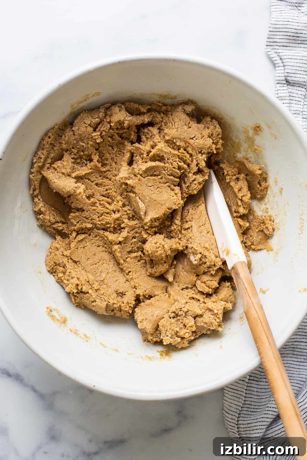 No-Bake Peanut Butter Twix Cups Recipe 4 Peanut butter cookie dough in a bowl with a wooden spoon.