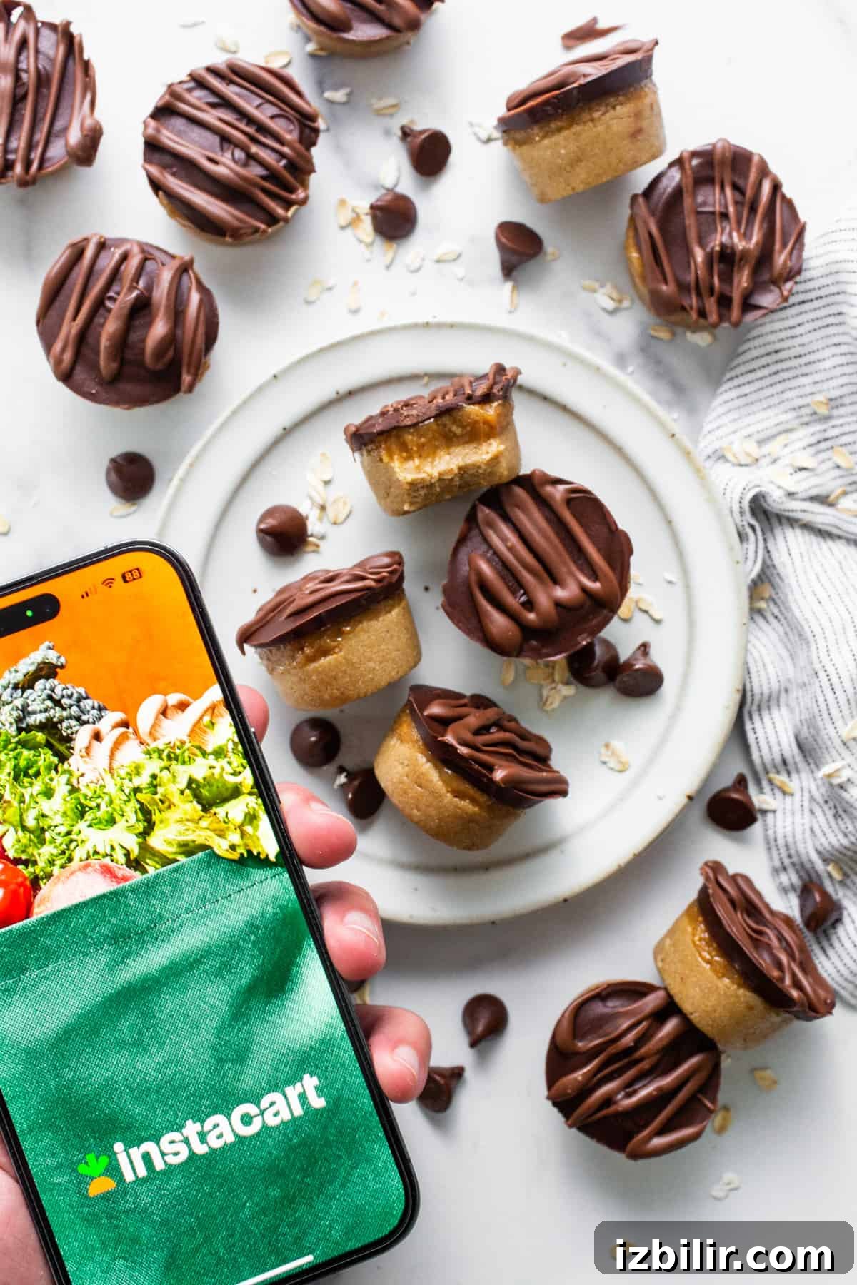 No-Bake Peanut Butter Twix Cups Recipe 6 A person holding a smartphone with a plate of cookies and brownies.