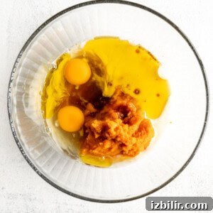 Classic Pumpkin Muffins Recipe with Warm Fall Spices 6 Two eggs in a glass bowl on a white background.