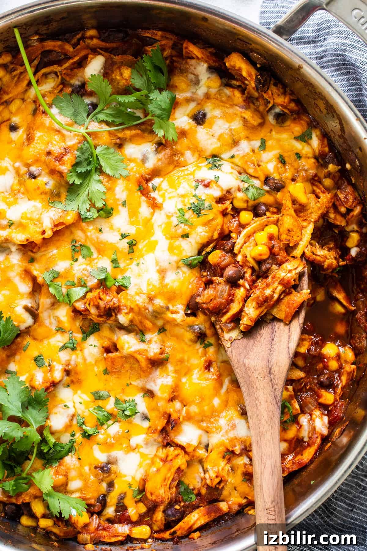 Mexican chicken enchilada in a pan with a wooden spoon.