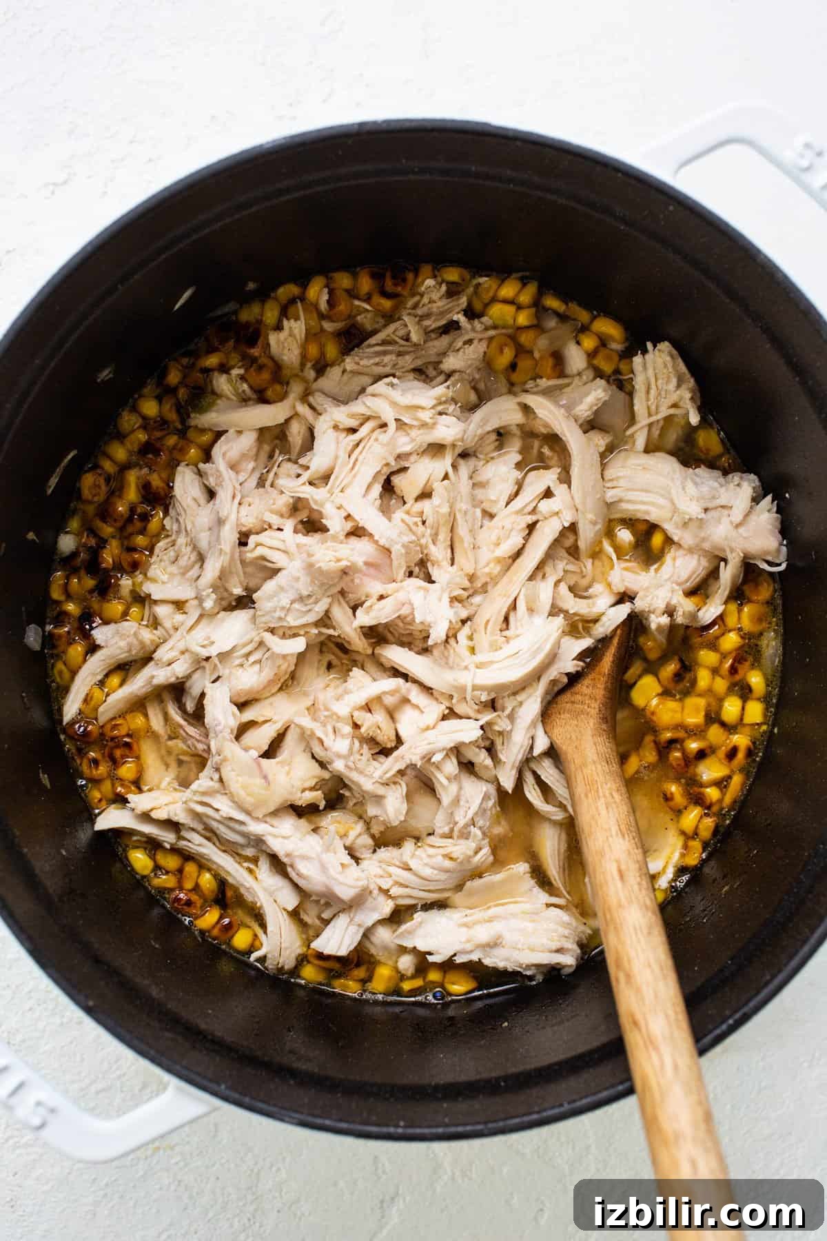 Fit Foodie Cooking Club October 2023: Recipes and Menus 3 Chicken and corn in a pan with a wooden spoon.