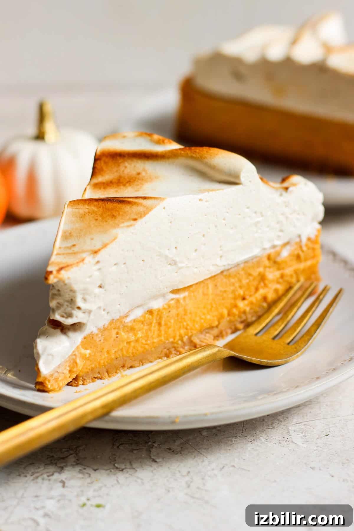 A slice of pumpkin pie on a plate with a gold fork.