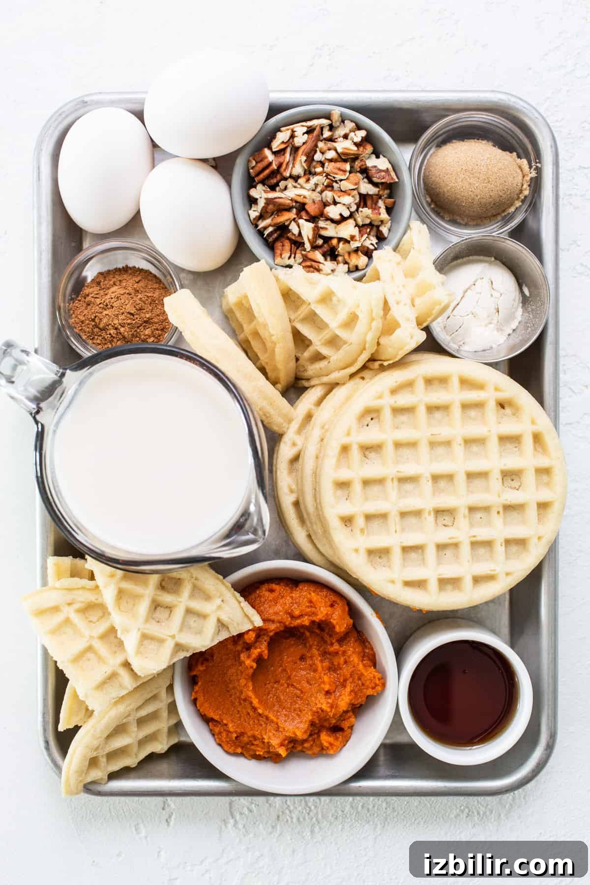 Waffles, eggs, milk and other ingredients on a tray.