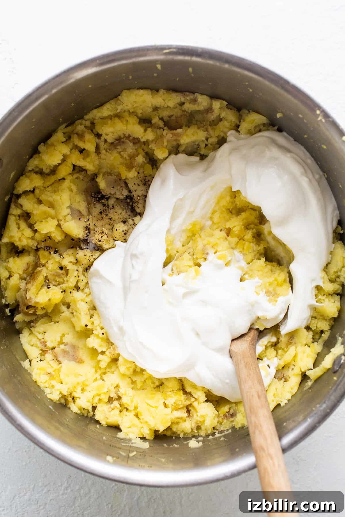 A bowl of batter with whipped cream and a wooden spoon.