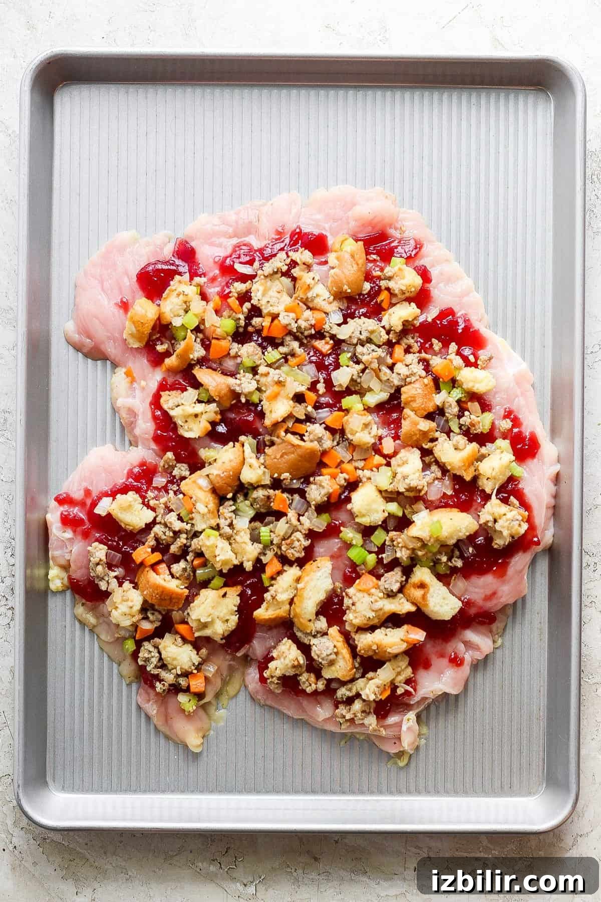 Thanksgiving Turkey Roulade Recipe with Italian Sausage Stuffing 5 A baking sheet with turkey and cranberry topping on it.