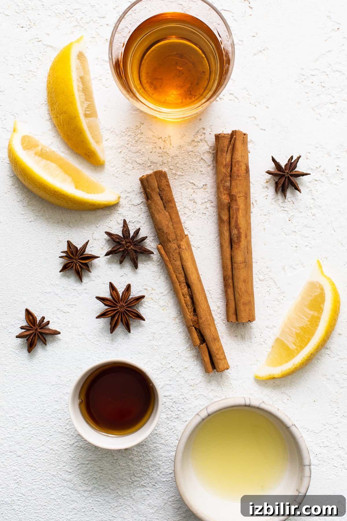 Maple Hot Toddy Recipe: Whiskey, Lemon & Warm Spices 3 Cinnamon, lemon, star anise and honey on a white background.