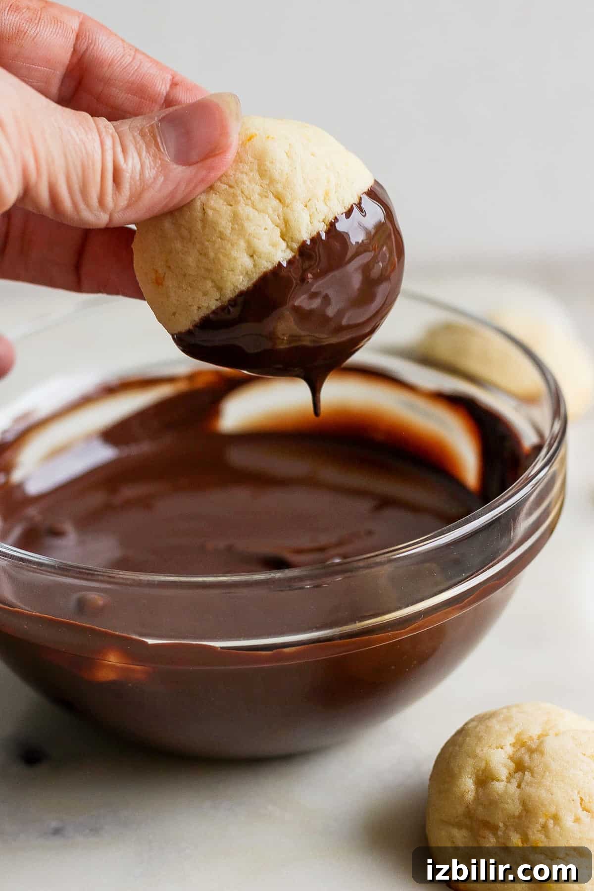 Zesty Chocolate Orange Ricotta Cookies 5 Person dipping a cookie into melted chocolate.