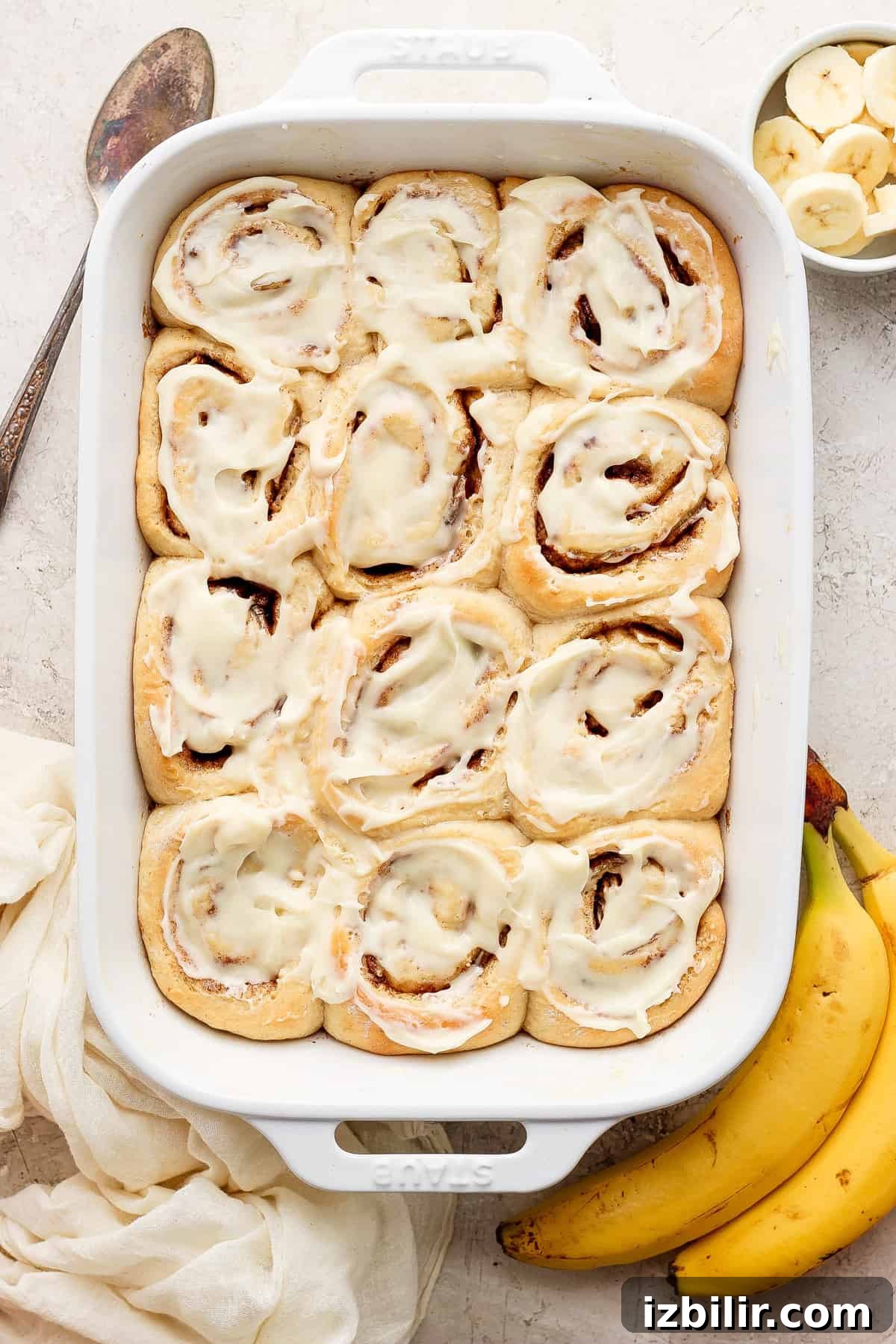Brown Butter Banana Bread Cinnamon Rolls Recipe 2 Cinnamon rolls in a baking dish with bananas.