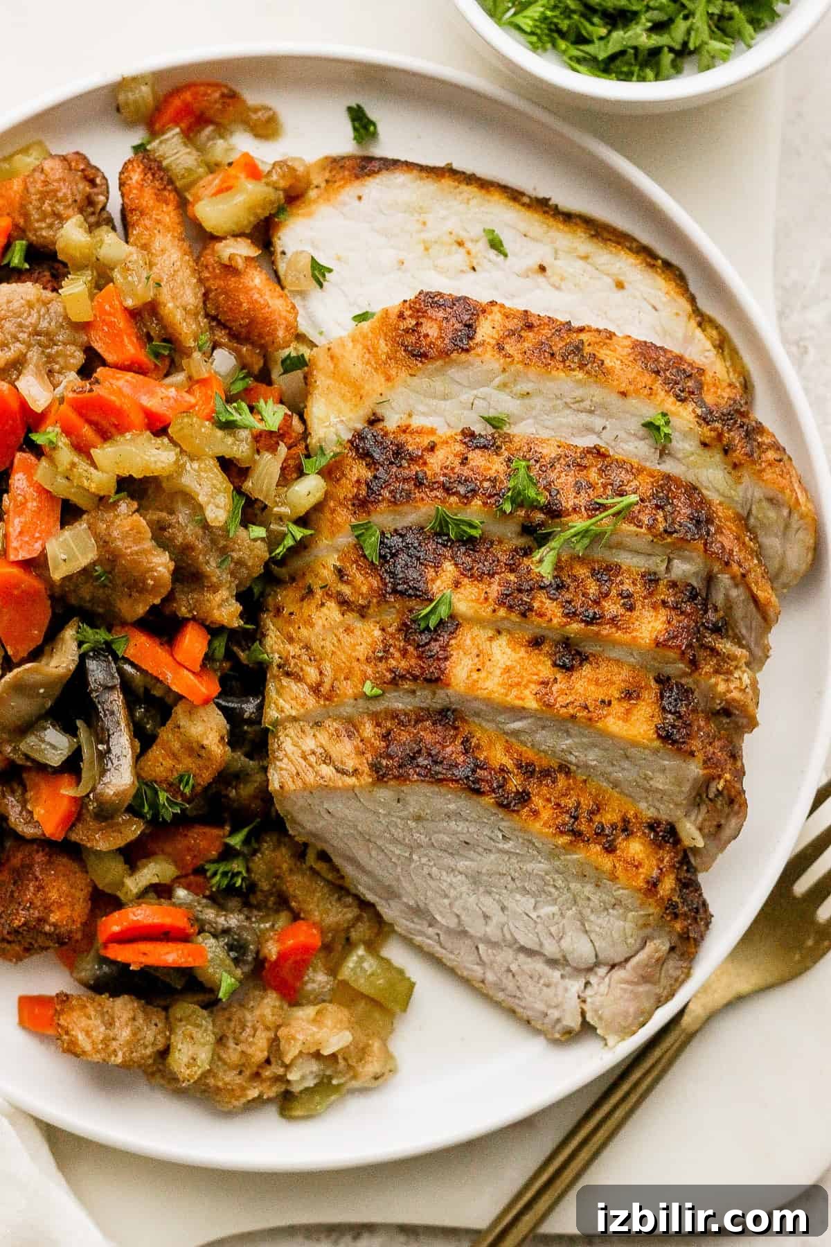 A plate with sliced pork tenderloin and vegetables on it.