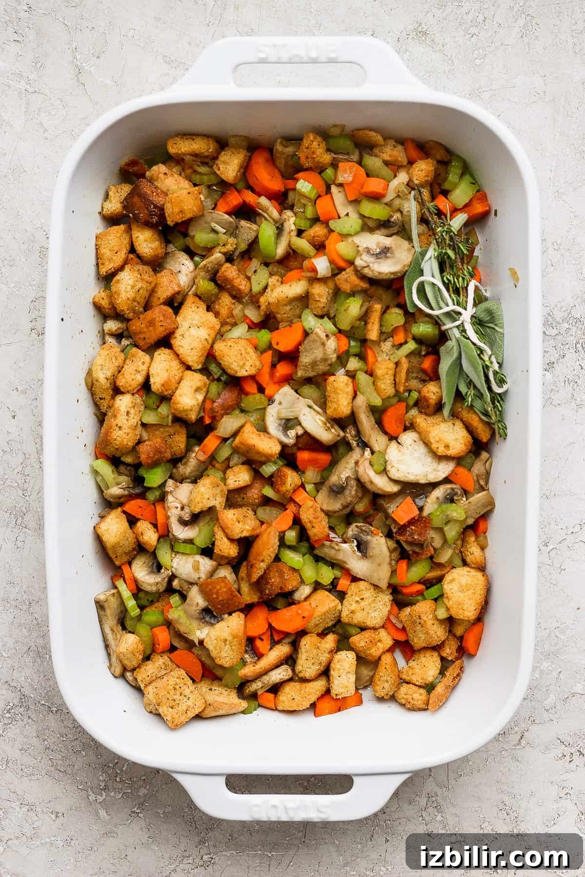 A white baking dish filled with stuffing and vegetables.