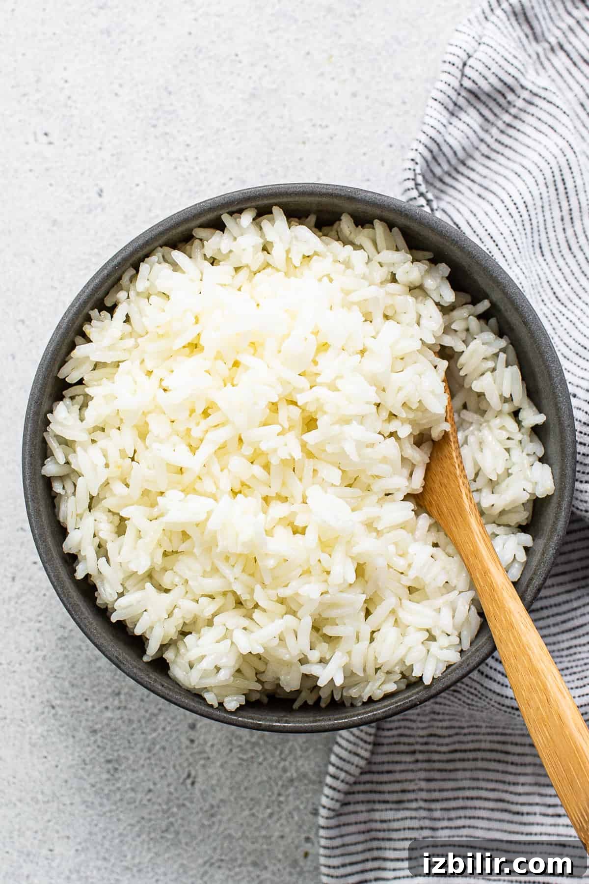 Fluffy Instant Pot White Rice in 12 Minutes 2 White rice in a bowl with a wooden spoon.
