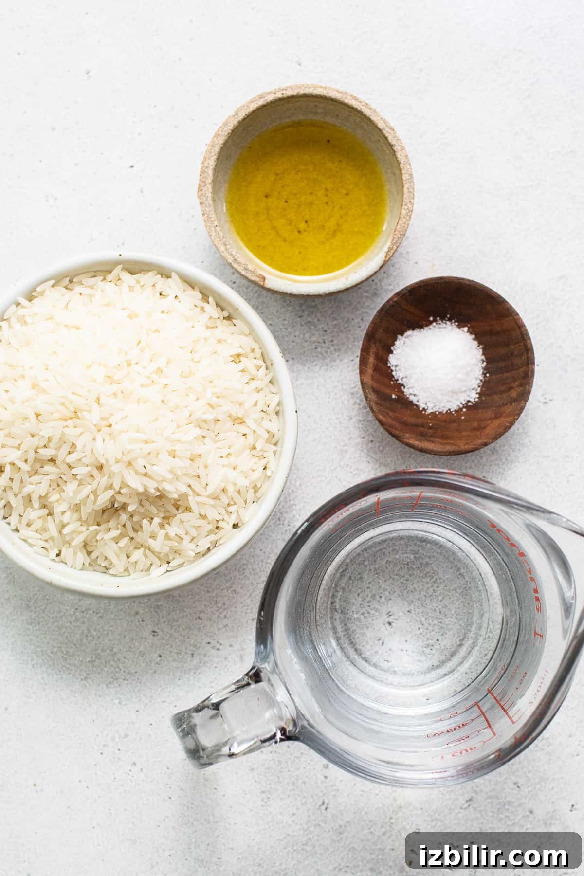 Fluffy Instant Pot White Rice in 12 Minutes 3 A bowl of rice, olive oil and salt on a white surface.