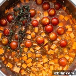 Roasted Sweet Potato and Mushroom Grain Bowl Recipe 7 A pan filled with tomatoes and a sprig of thyme.