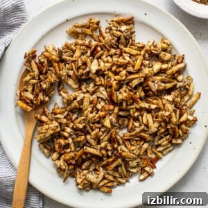 Roasted Sweet Potato and Mushroom Grain Bowl Recipe 8 Roasted peanuts on a white plate with a wooden spoon.