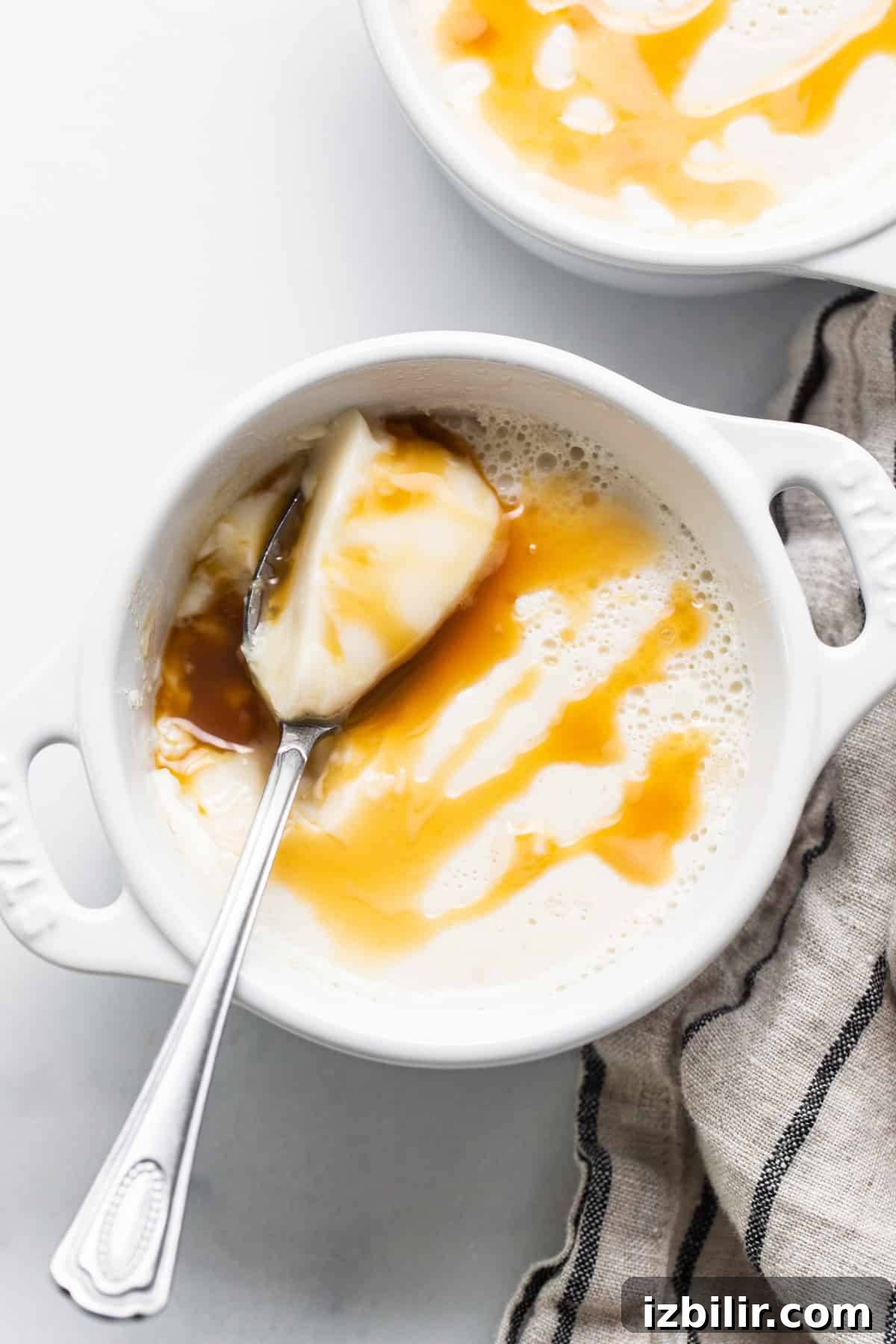 A bowl of oatmeal with caramel sauce and a spoon.