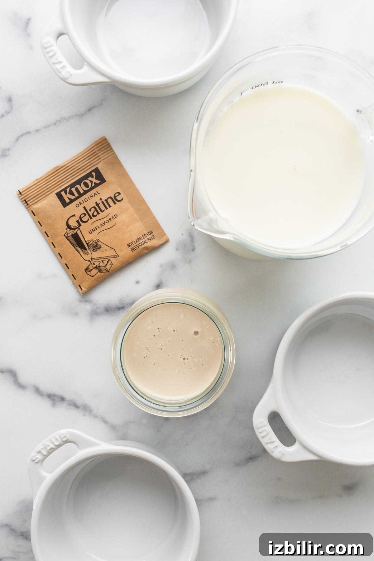 A bowl of milk, a spoon, and a packet of powdered milk.