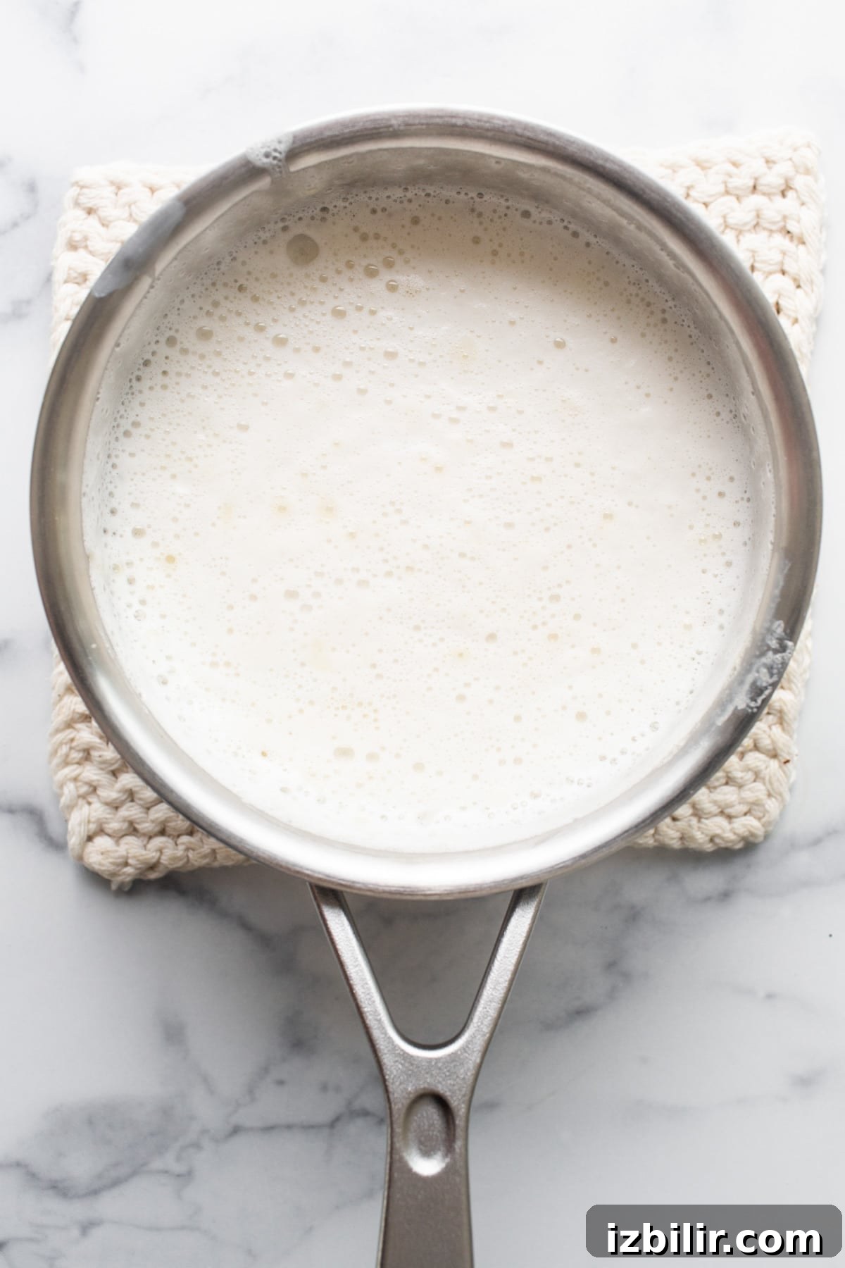 A pan with milk in it on a marble countertop.