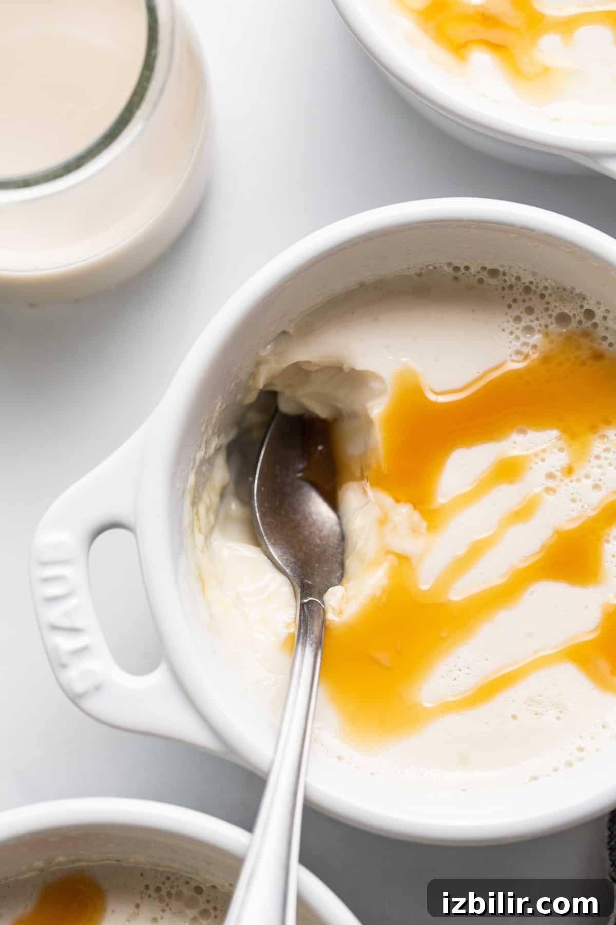 A bowl of ice cream with caramel sauce and a spoon.