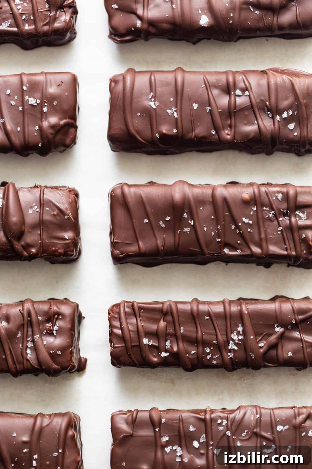 A row of chocolate covered bars on a white surface.