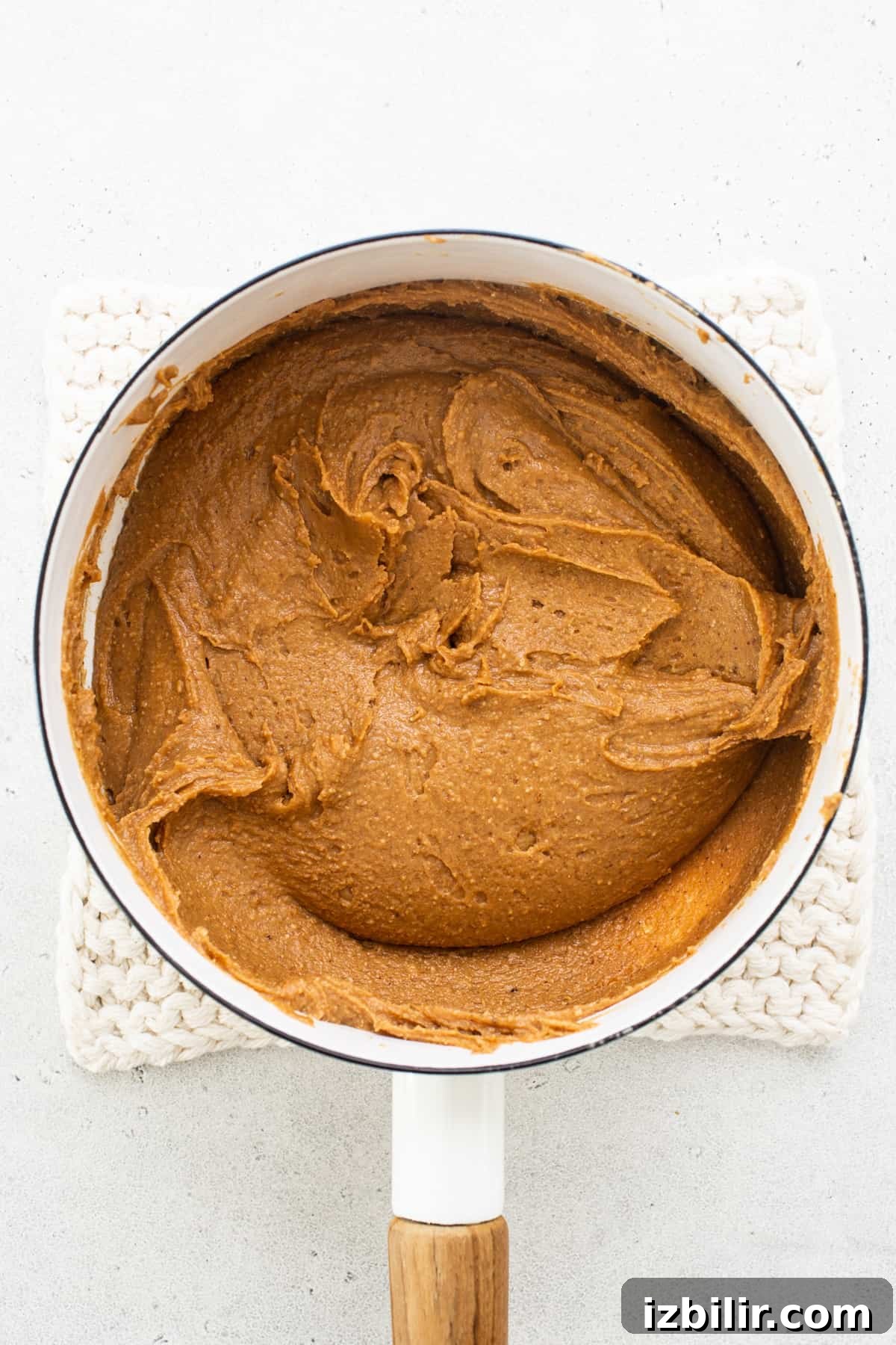 Pumpkin butter in a pan with a wooden spoon.