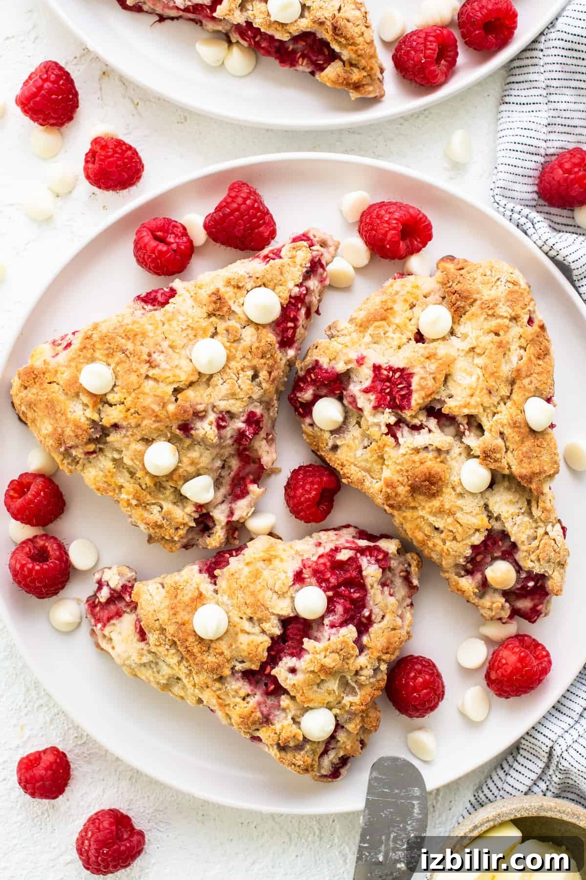 Raspberries and white chocolate scones on a white plate.