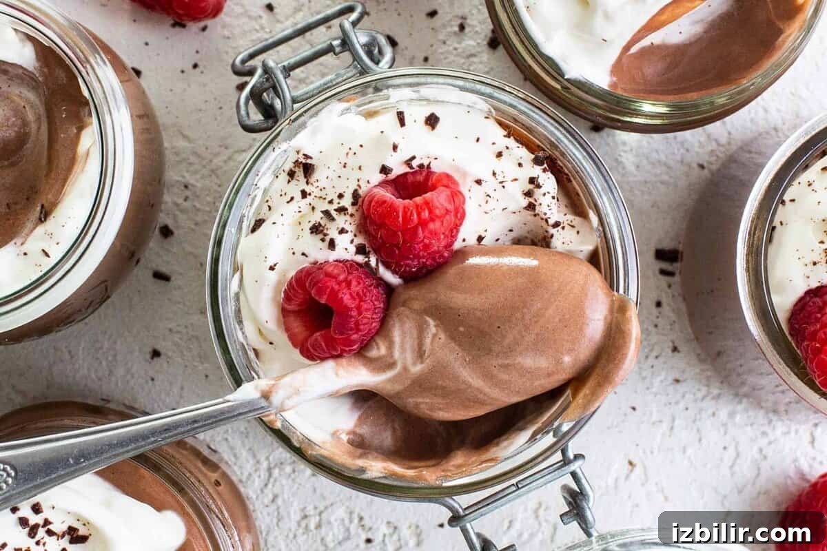 Chocolate mousse in jars with whipped cream and raspberries.