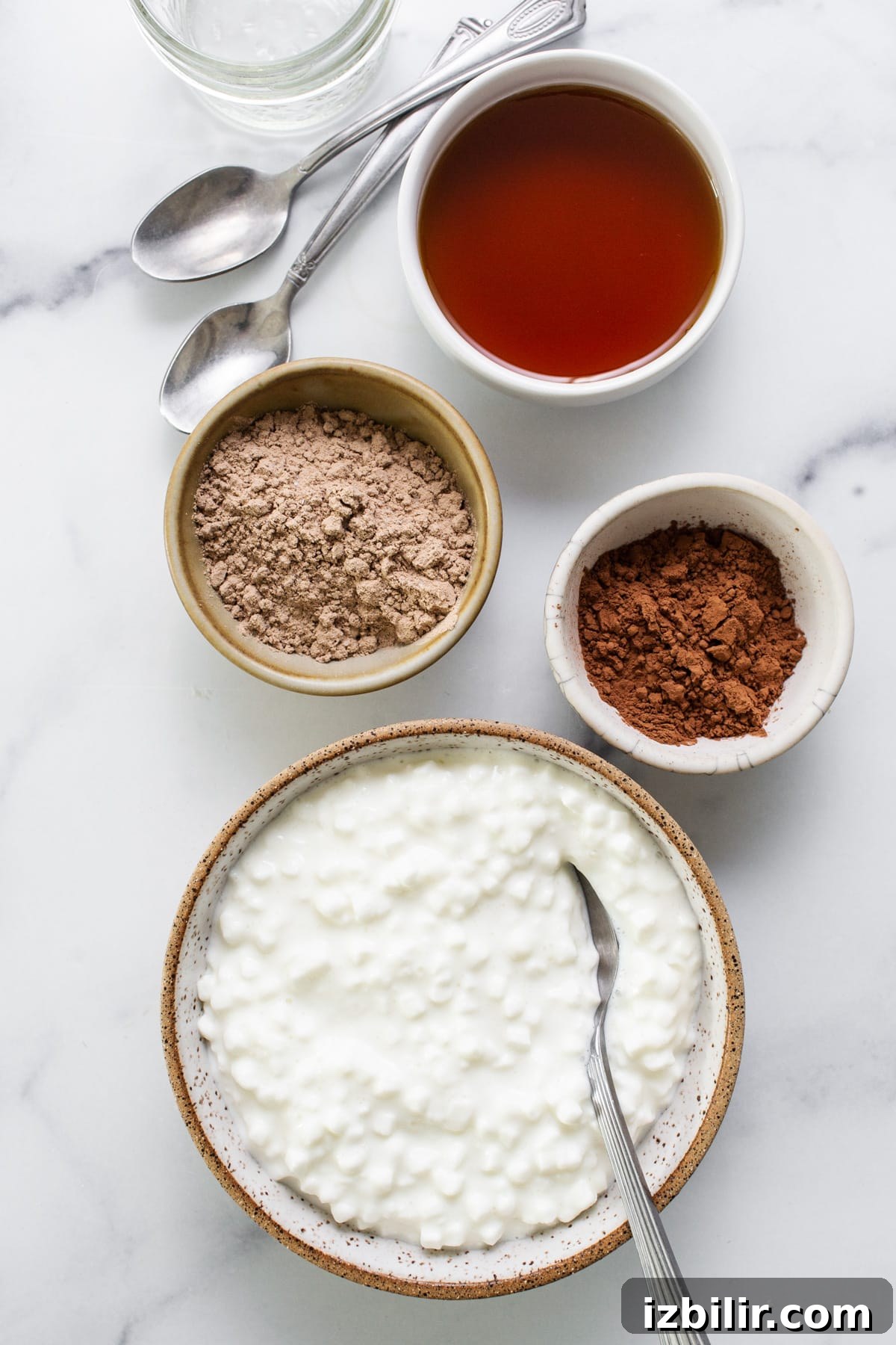 A bowl of yogurt with ingredients on a marble table.