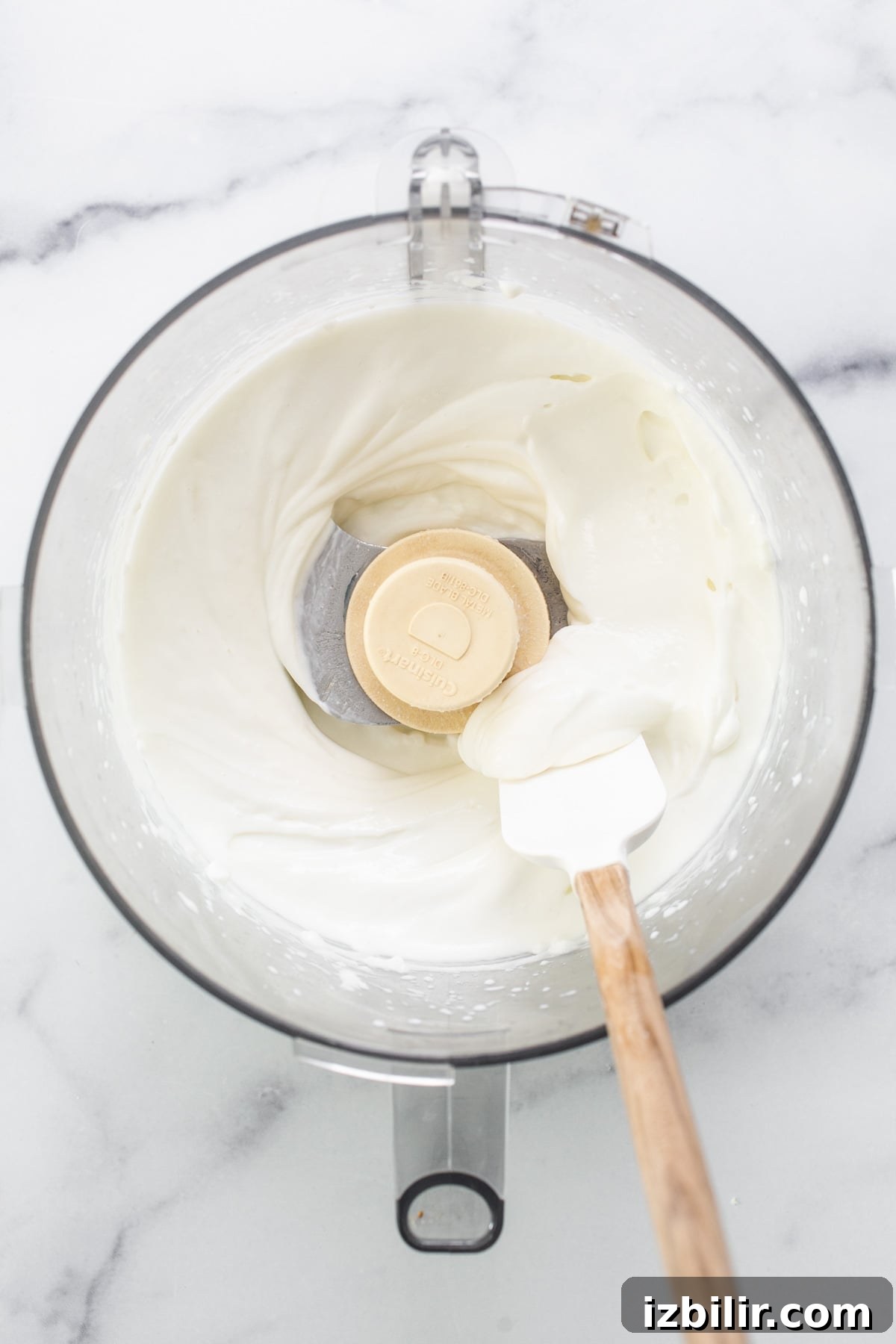 Whipped cream in a mixing bowl with a wooden spoon.