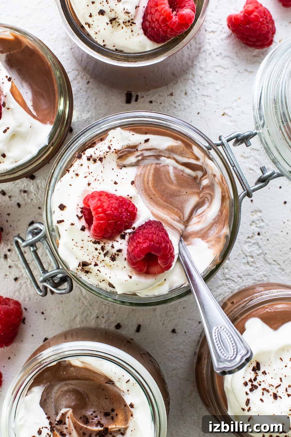 Chocolate mousse in jars with raspberries and whipped cream.