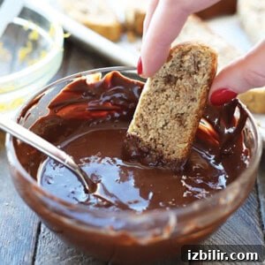 Dipping an almond flour biscotti into melted chocolate.