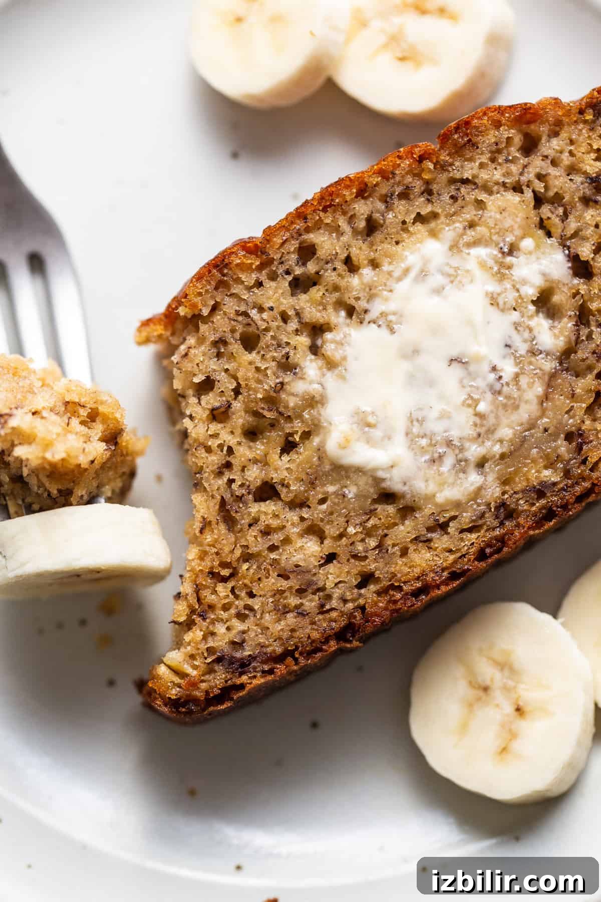 A slice of banana bread on a plate with a fork.