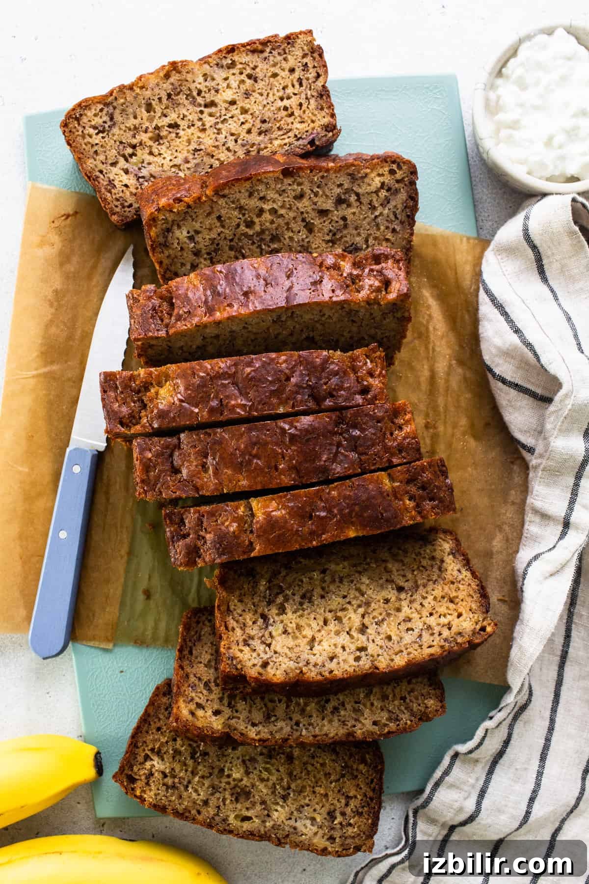 Sliced banana bread on a cutting board with a knife.