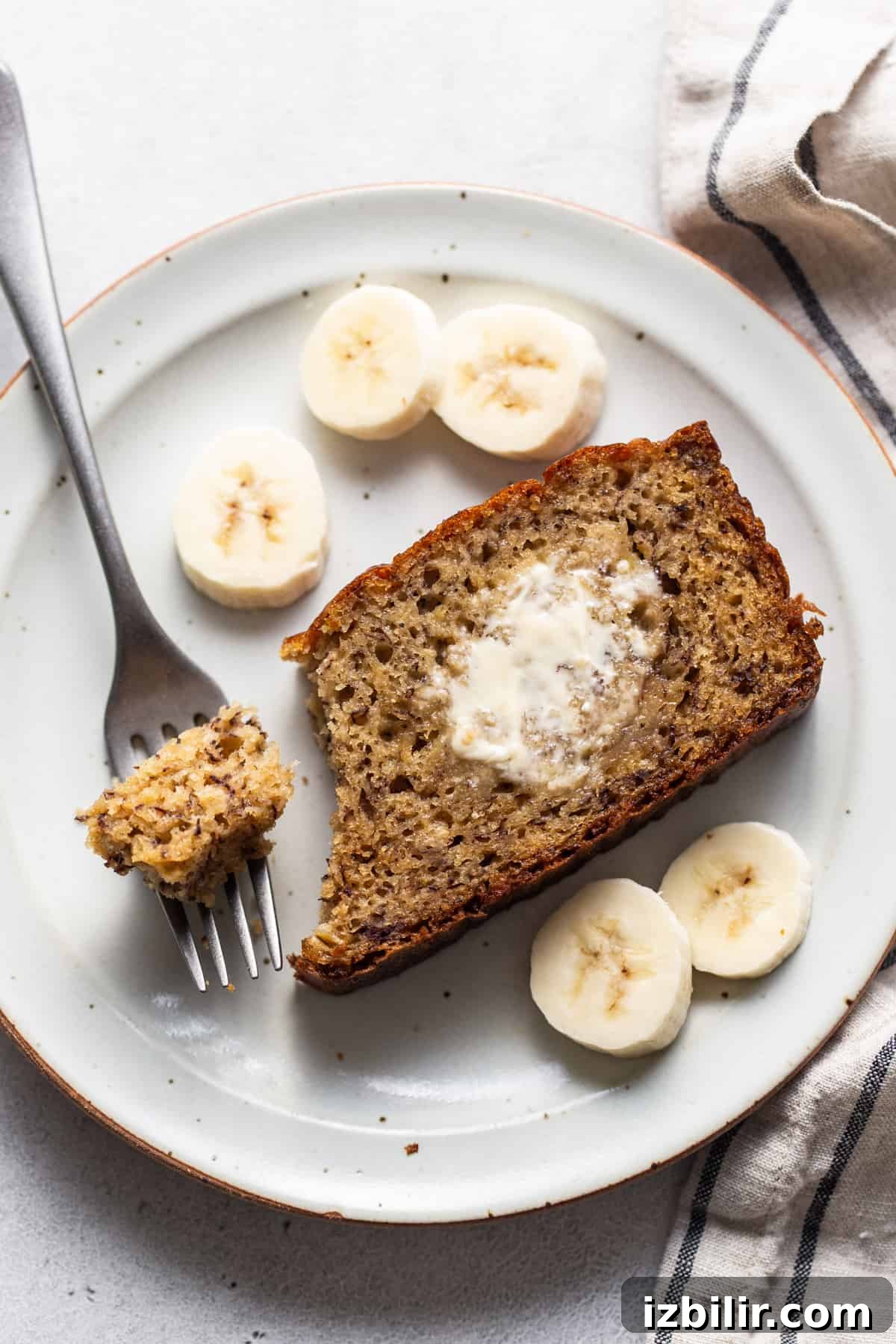 A slice of banana bread on a plate with a fork.