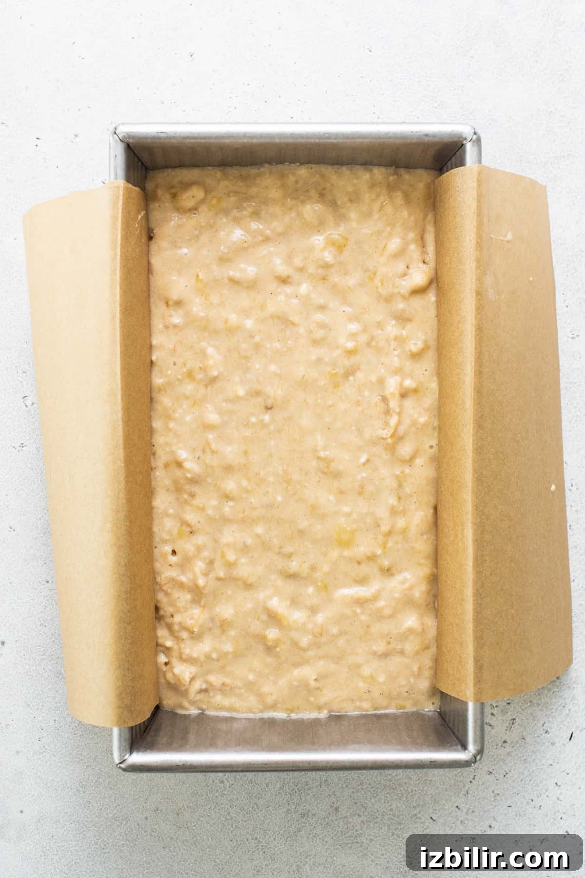 Banana bread in a pan on a white surface.