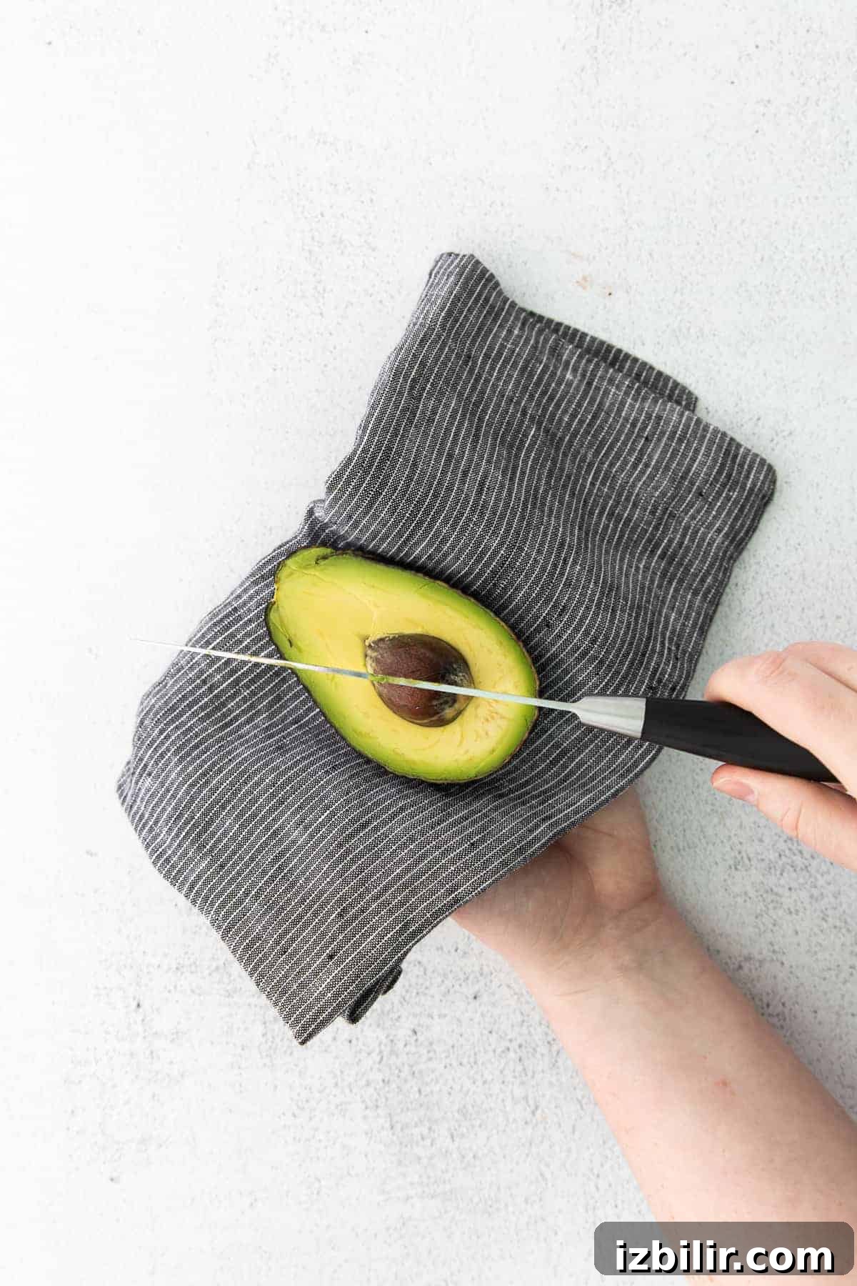Salmon Stuffed Avocados Recipe with Dill and Lemon 5 Cutting the pit out of a ripe avocado.